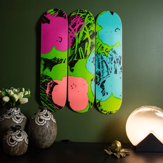 Flowers (Green/Pink) by Andy Warhol displayed as a vibrant triptych on skateboards in a modern interior setting