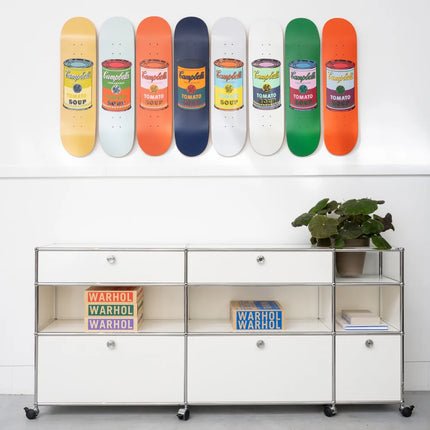 Set of 8 Colored Campbell's Soup skateboards by Andy Warhol displayed above a white modern cabinet in a contemporary interior.