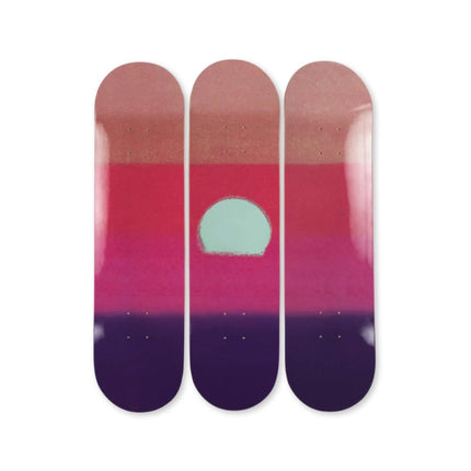 Three skateboard decks side by side featuring a minimalist gradient design titled "Sunset (Purple)" by Andy Warhol