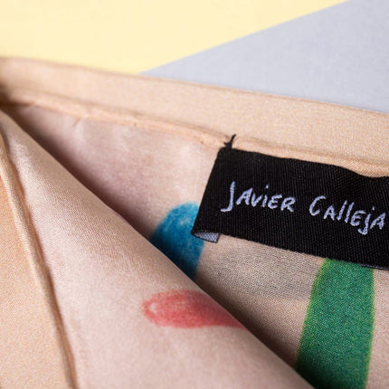 Detail of “Rules” by Javier Calleja showing silk fabric texture with printed colorful motifs and artist label sewn on corner.