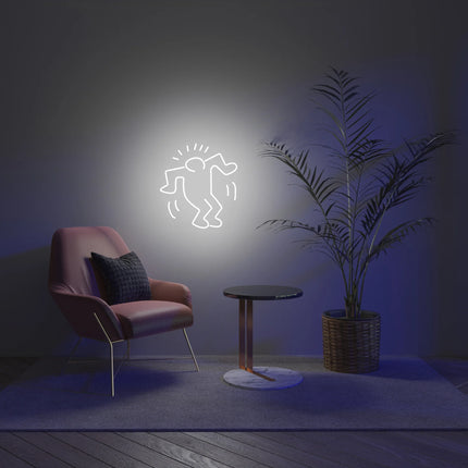 Lifestyle view of "Dancing Man YP x Keith Haring" neon lamp displayed on wall with chair and plant in modern room