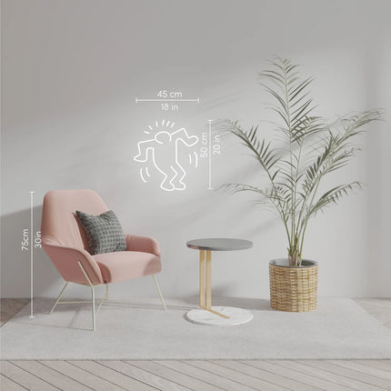 Lifestyle view of "Dancing Man YP x Keith Haring" neon lamp displayed on a white wall above modern furniture and plant.