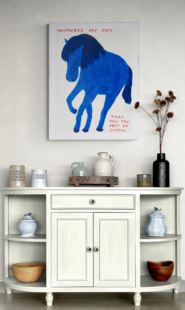 Full artwork view of David Shrigley’s “Witness my joy” print showing a blue horse and red text in a contemporary interior setting